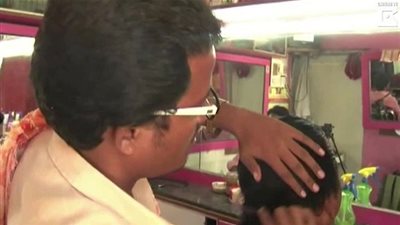 حلاق هندي يستخدم تقنية جديدة لقص شعر زبائنه بواسطة شمعة مشتعلة! (فيديو)